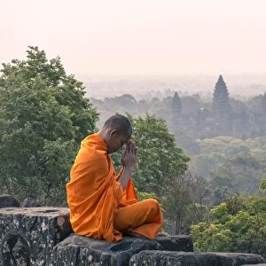 Cambodia, Siem Reap, Angkor Wat complex. Monk meditating with Angor wat temple in the background